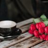 faceless couple with coffee and rose bouquet in cafeteria