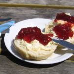 Cup of tea with scone and cream, jam on top